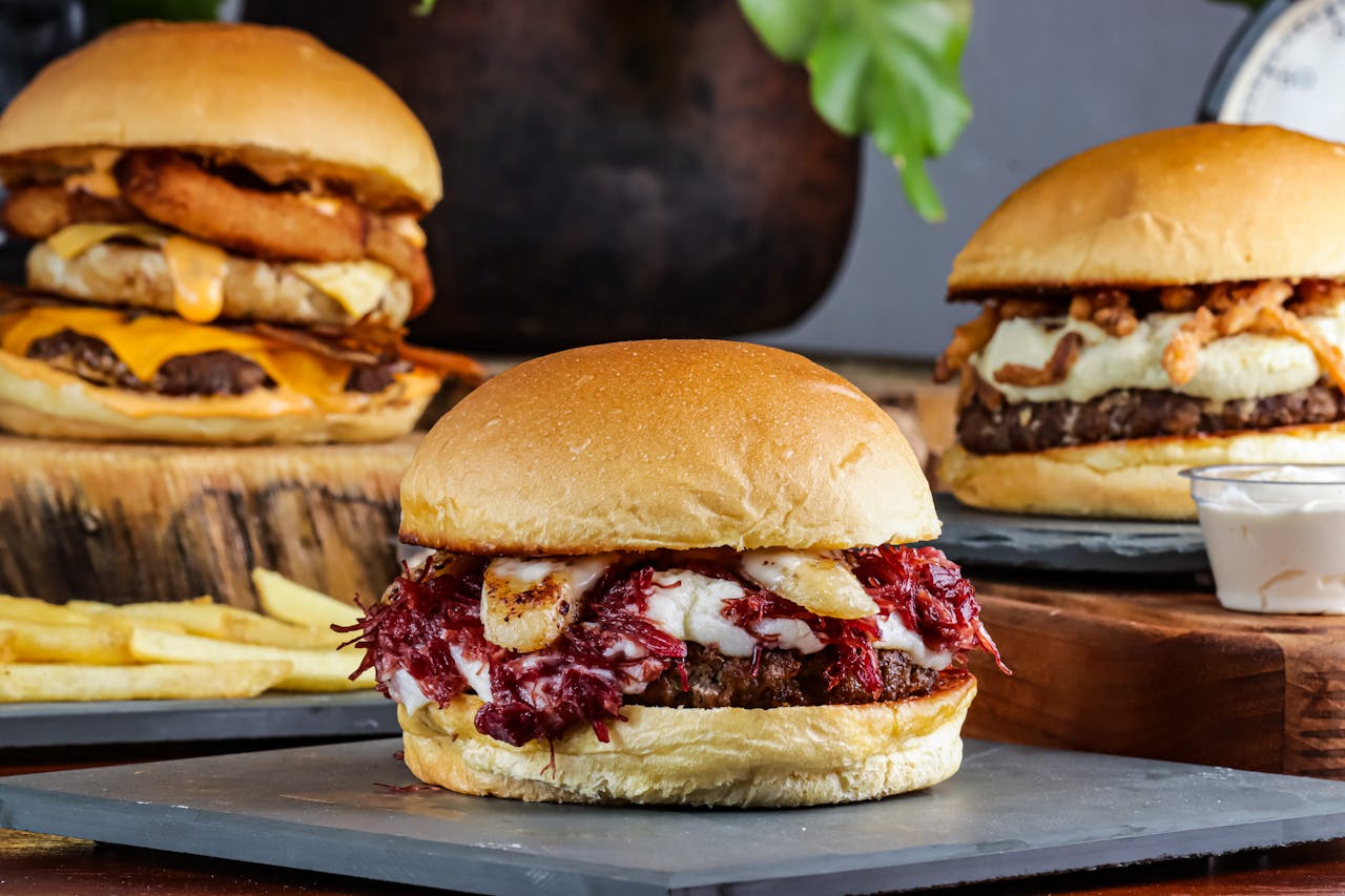 Mouthwatering capture of three gourmet burgers with diverse toppings and a side of fries.